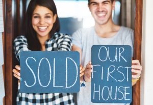 Portrait of a happy couple holding signs as they move into their new house